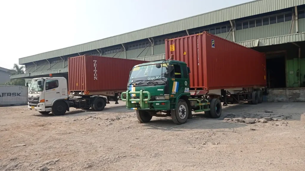 Commercial shipping containers and trucks at distribution center operated by Inti Mandiri Jayatama