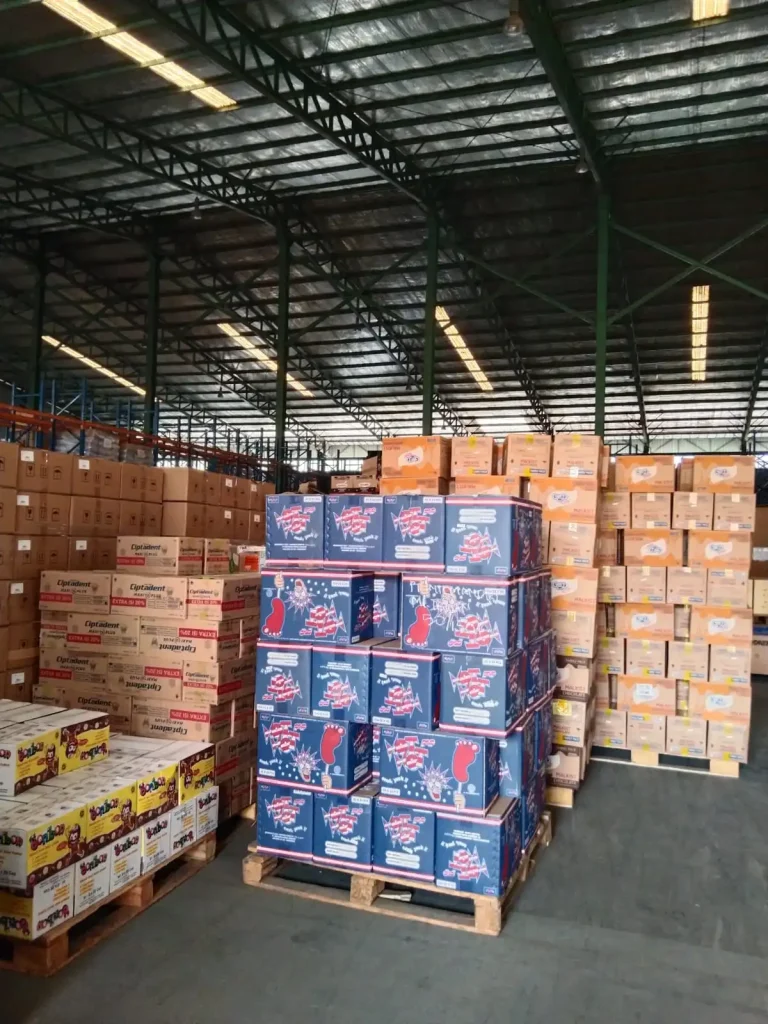 Large warehouse interior with stacked product inventory and organized storage system by Inti Mandiri Jayatama